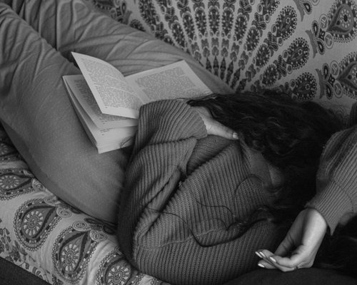 person reading a book comfortably on a couch before sleep